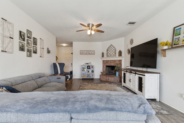 living area featuring ceiling fan, a fireplace, visible vents, and wood finished floors