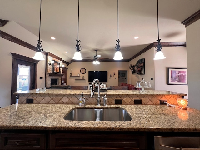 kitchen with ornamental molding, open floor plan, a fireplace, and a sink