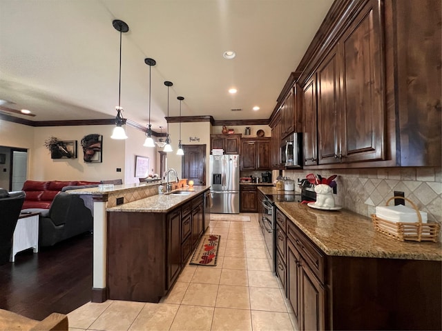 kitchen with light tile patterned floors, tasteful backsplash, appliances with stainless steel finishes, open floor plan, and a sink