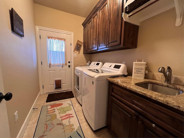 laundry room featuring light tile patterned flooring, a sink, baseboards, washer and dryer, and cabinet space