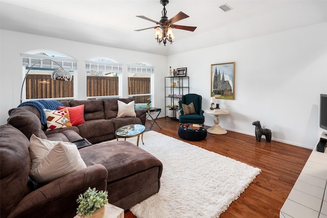 living room with dark wood-style floors, baseboards, visible vents, and a ceiling fan