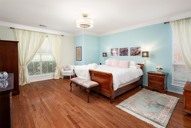 bedroom with ornamental molding, visible vents, and wood finished floors