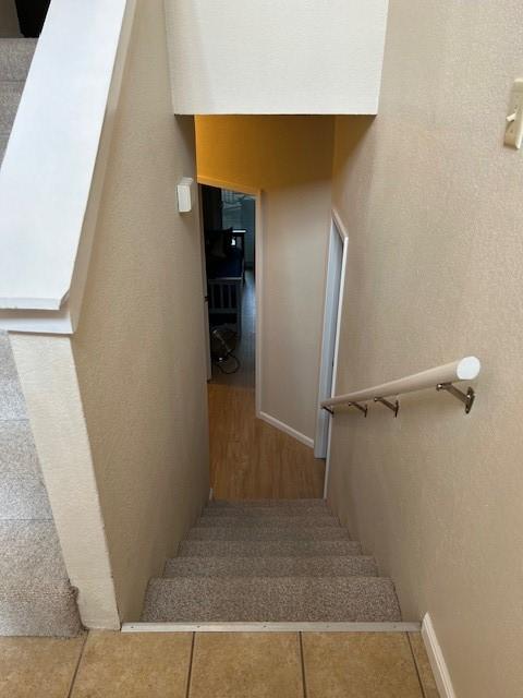 stairs with baseboards and tile patterned floors