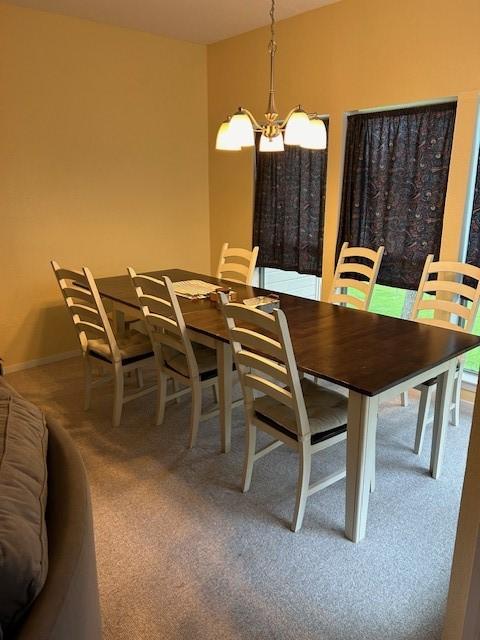 dining area with carpet, baseboards, and a notable chandelier