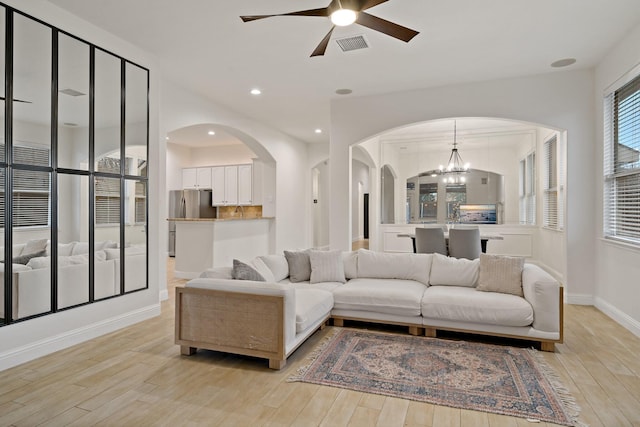 living area with light wood finished floors, recessed lighting, visible vents, and ceiling fan with notable chandelier