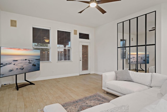 living area featuring ceiling fan, baseboards, and wood finished floors