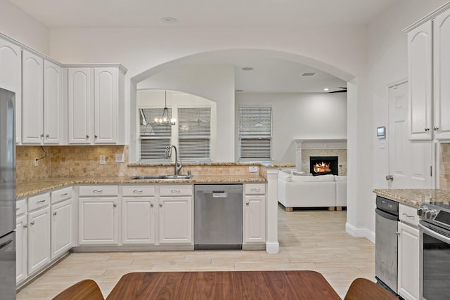 kitchen with a sink, white cabinets, appliances with stainless steel finishes, backsplash, and wood tiled floor