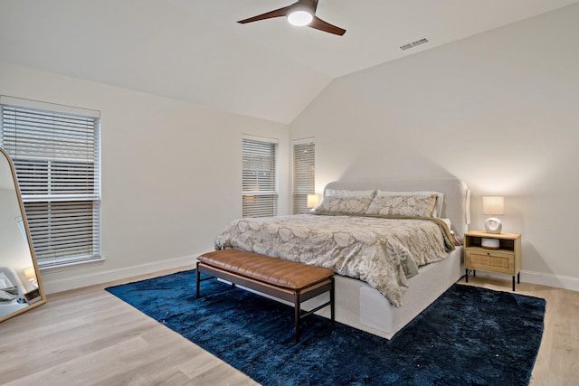 bedroom with wood finished floors, a ceiling fan, visible vents, vaulted ceiling, and baseboards