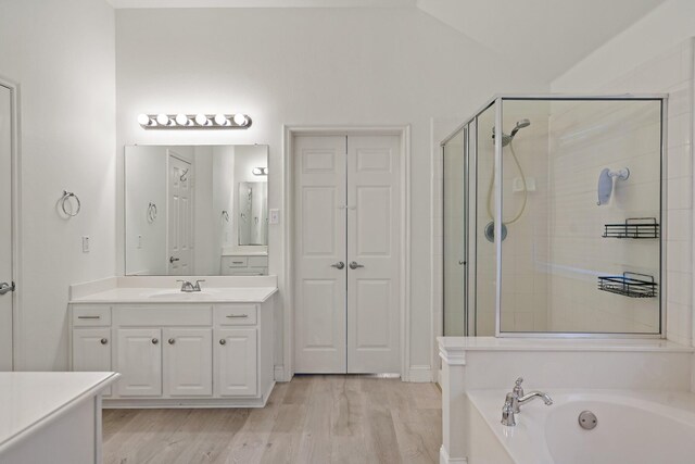 bathroom with wood finished floors, a garden tub, vaulted ceiling, vanity, and a shower stall