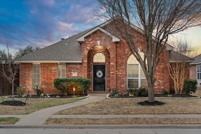 traditional home with a shingled roof and brick siding