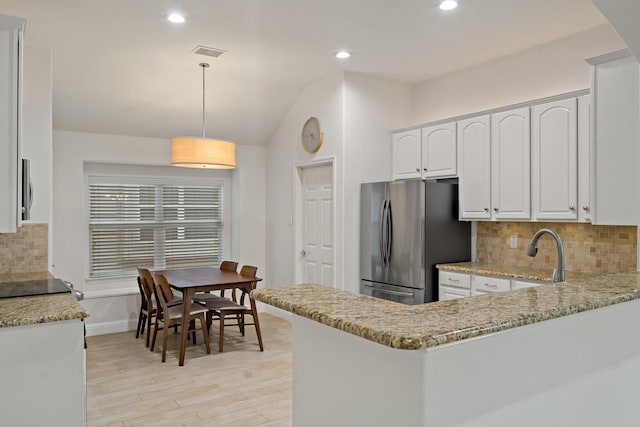 kitchen with white cabinetry, freestanding refrigerator, visible vents, and light stone countertops