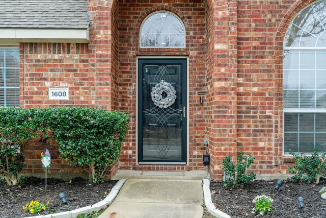 property entrance with brick siding and roof with shingles