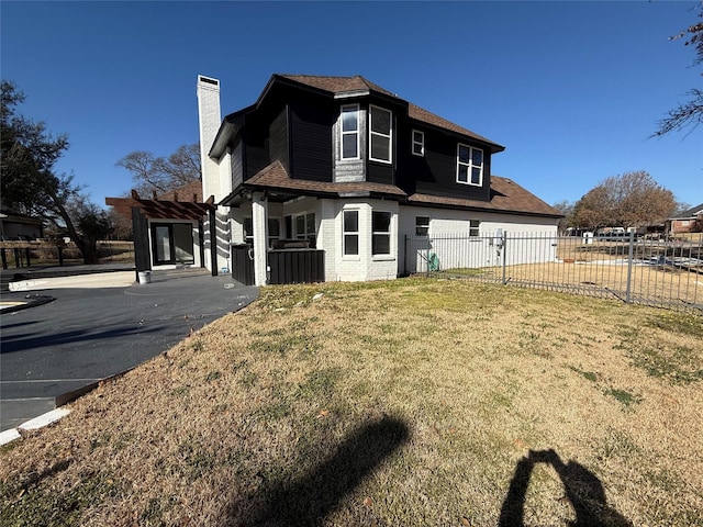 view of front facade featuring brick siding, a chimney, a front yard, fence, and a pergola