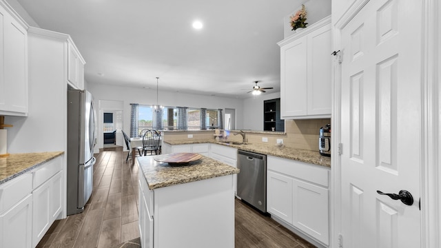 kitchen with dark wood finished floors, decorative backsplash, a peninsula, stainless steel appliances, and white cabinetry