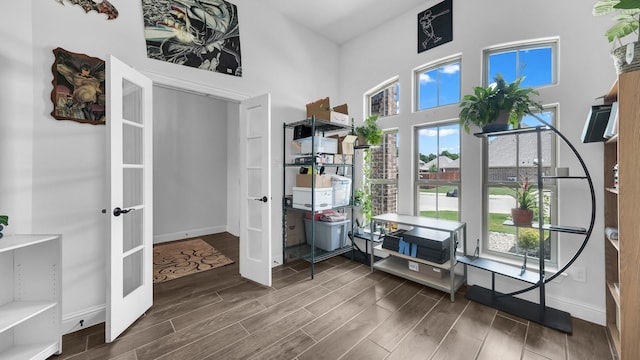 interior space with wood tiled floor, a high ceiling, baseboards, and french doors