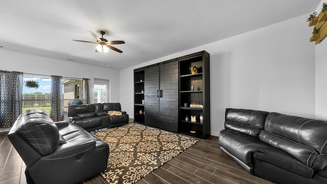 living area with visible vents, wood finish floors, a ceiling fan, and baseboards