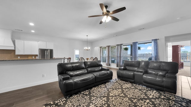 living room with ceiling fan with notable chandelier, a wealth of natural light, dark wood-style flooring, and visible vents