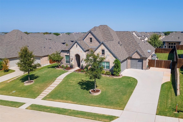 french country style house with a garage, a front yard, concrete driveway, and fence