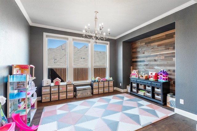 game room with baseboards, ornamental molding, a chandelier, and wood finished floors