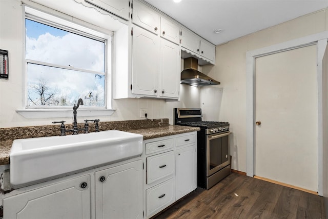 kitchen featuring a sink, white cabinetry, wall chimney exhaust hood, dark countertops, and gas range