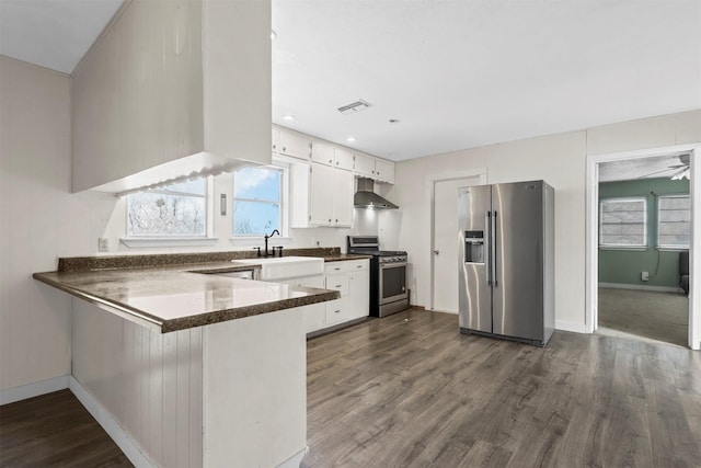 kitchen featuring visible vents, appliances with stainless steel finishes, a peninsula, ventilation hood, and a sink