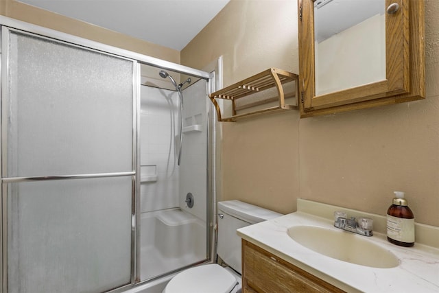 bathroom with toilet, vanity, and a shower with shower door