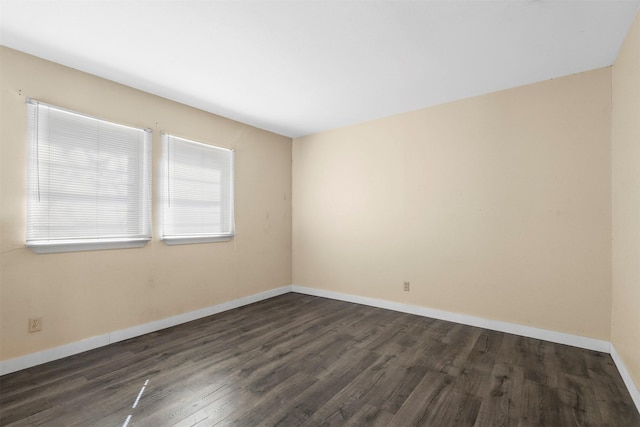 unfurnished room featuring baseboards and dark wood-type flooring