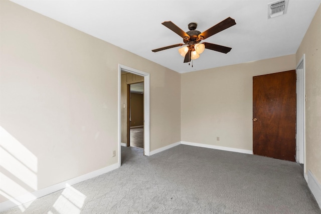 carpeted spare room featuring ceiling fan, visible vents, and baseboards