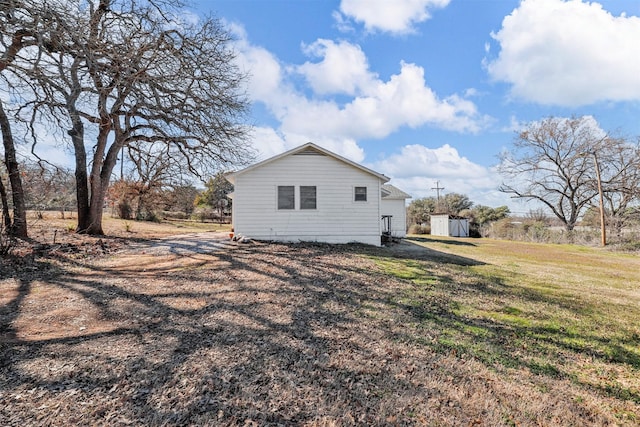 back of property with an outbuilding, a yard, and a storage shed