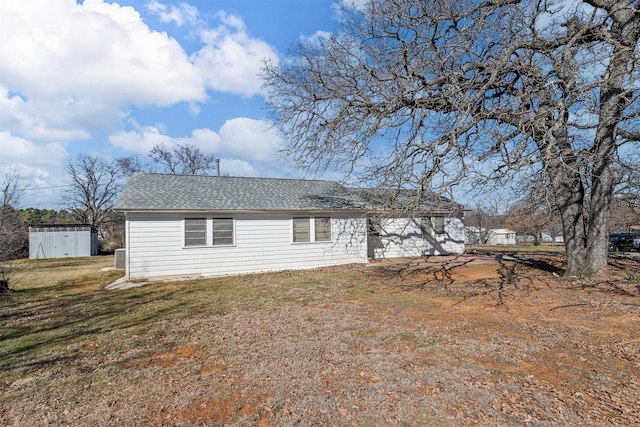 back of property with roof with shingles and a lawn