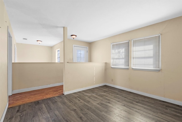 spare room with wood finished floors, visible vents, and baseboards