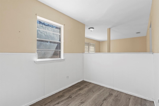 empty room featuring a wainscoted wall and wood finished floors