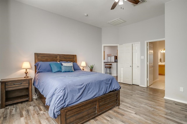 bedroom featuring a ceiling fan, ensuite bath, light wood-style floors, and visible vents