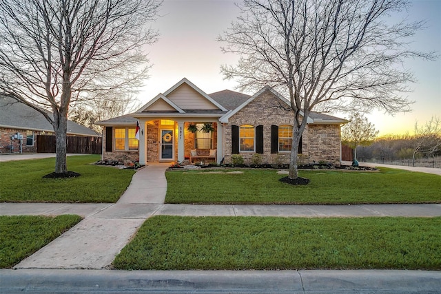 craftsman-style home with brick siding, a front lawn, and fence