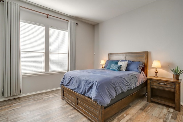 bedroom featuring multiple windows, light wood-type flooring, and baseboards