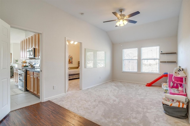 rec room with ceiling fan, baseboards, light wood-style flooring, and lofted ceiling