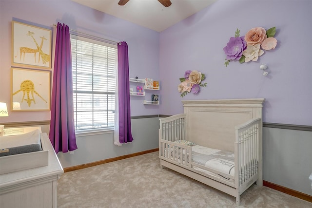 bedroom featuring baseboards, a nursery area, ceiling fan, and carpet