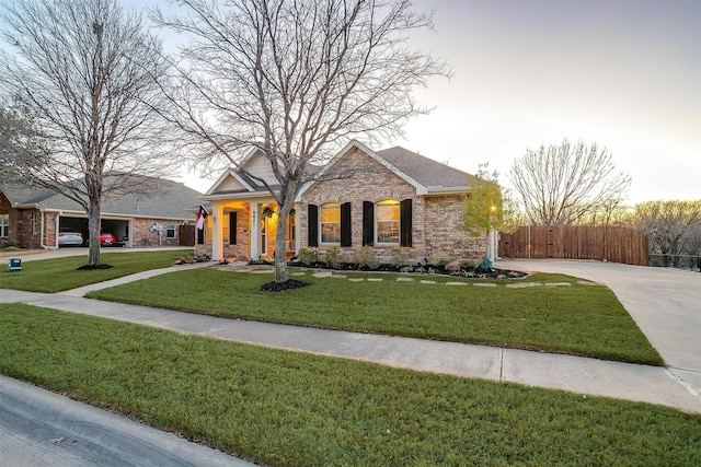 view of front of house featuring brick siding, a front lawn, and fence