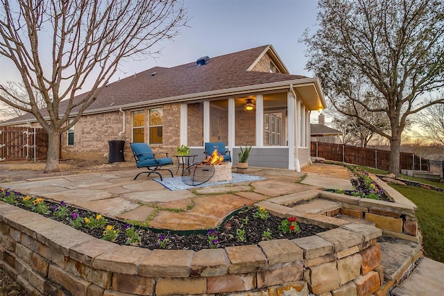 rear view of house featuring fence, a patio area, brick siding, and an outdoor fire pit