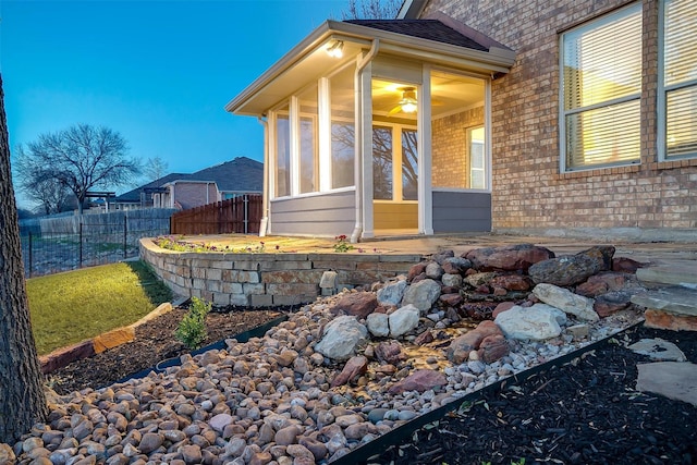 view of exterior entry with brick siding and fence