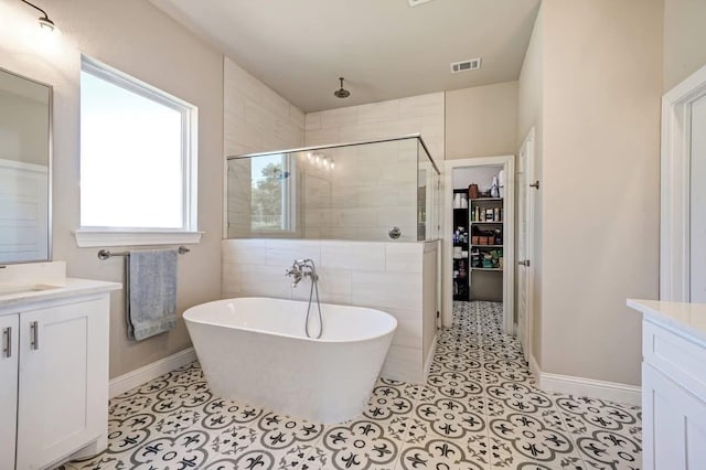 bathroom with visible vents, a freestanding bath, vanity, and a shower stall