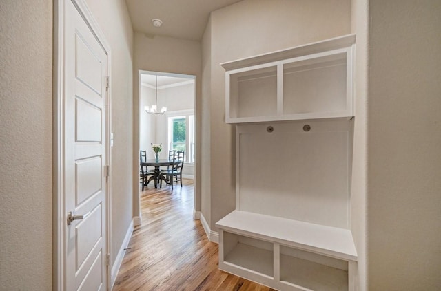 mudroom featuring an inviting chandelier, light wood-style flooring, and baseboards