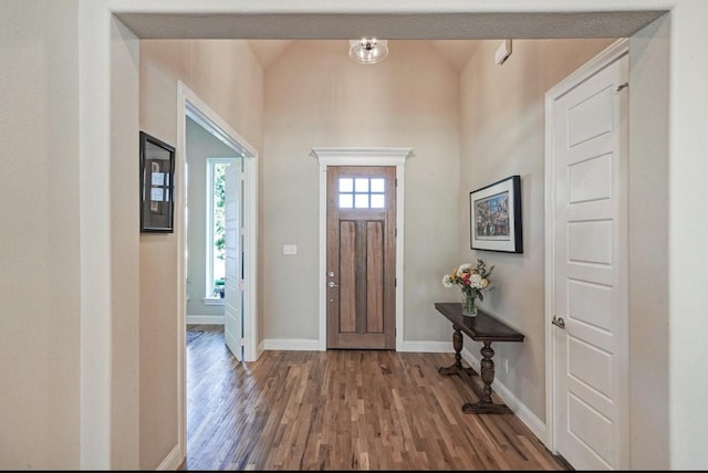 entryway with vaulted ceiling, baseboards, and wood finished floors