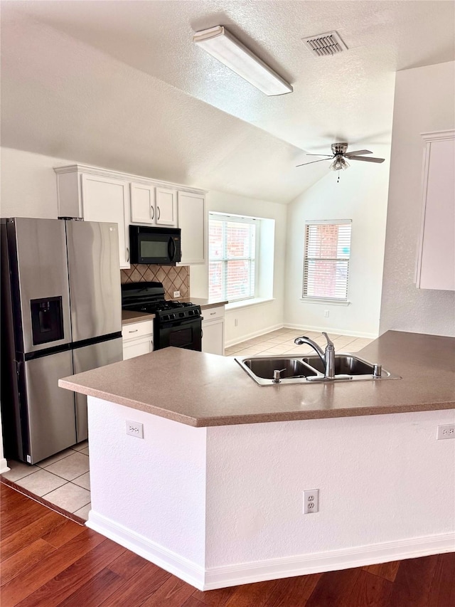 kitchen with a sink, visible vents, light wood-style floors, white cabinets, and black appliances