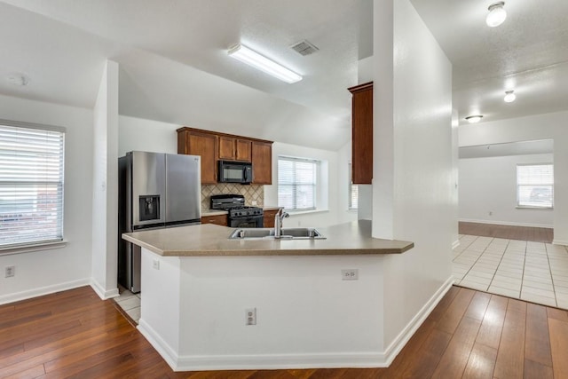 kitchen featuring black appliances, hardwood / wood-style floors, a sink, and visible vents