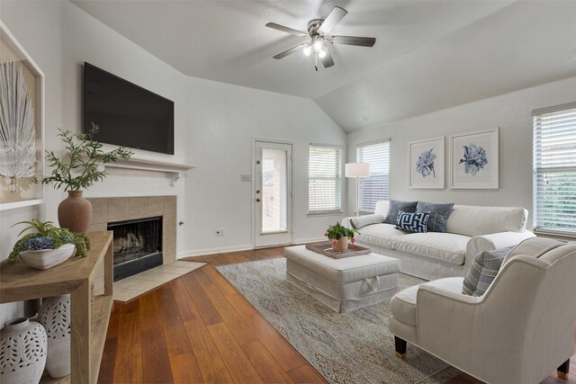 living room with hardwood / wood-style flooring, a fireplace, a ceiling fan, baseboards, and vaulted ceiling