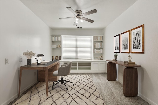 office space featuring a ceiling fan, light carpet, and baseboards