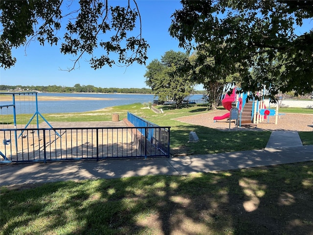 view of community featuring playground community, a lawn, and a water view