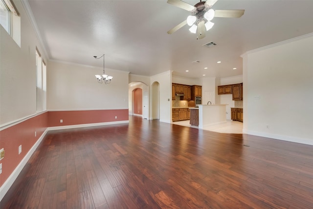 unfurnished living room featuring ceiling fan with notable chandelier, wood finished floors, visible vents, baseboards, and ornamental molding