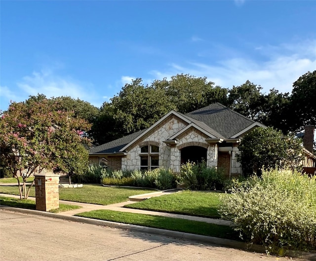 view of front of property featuring roof with shingles and a front yard